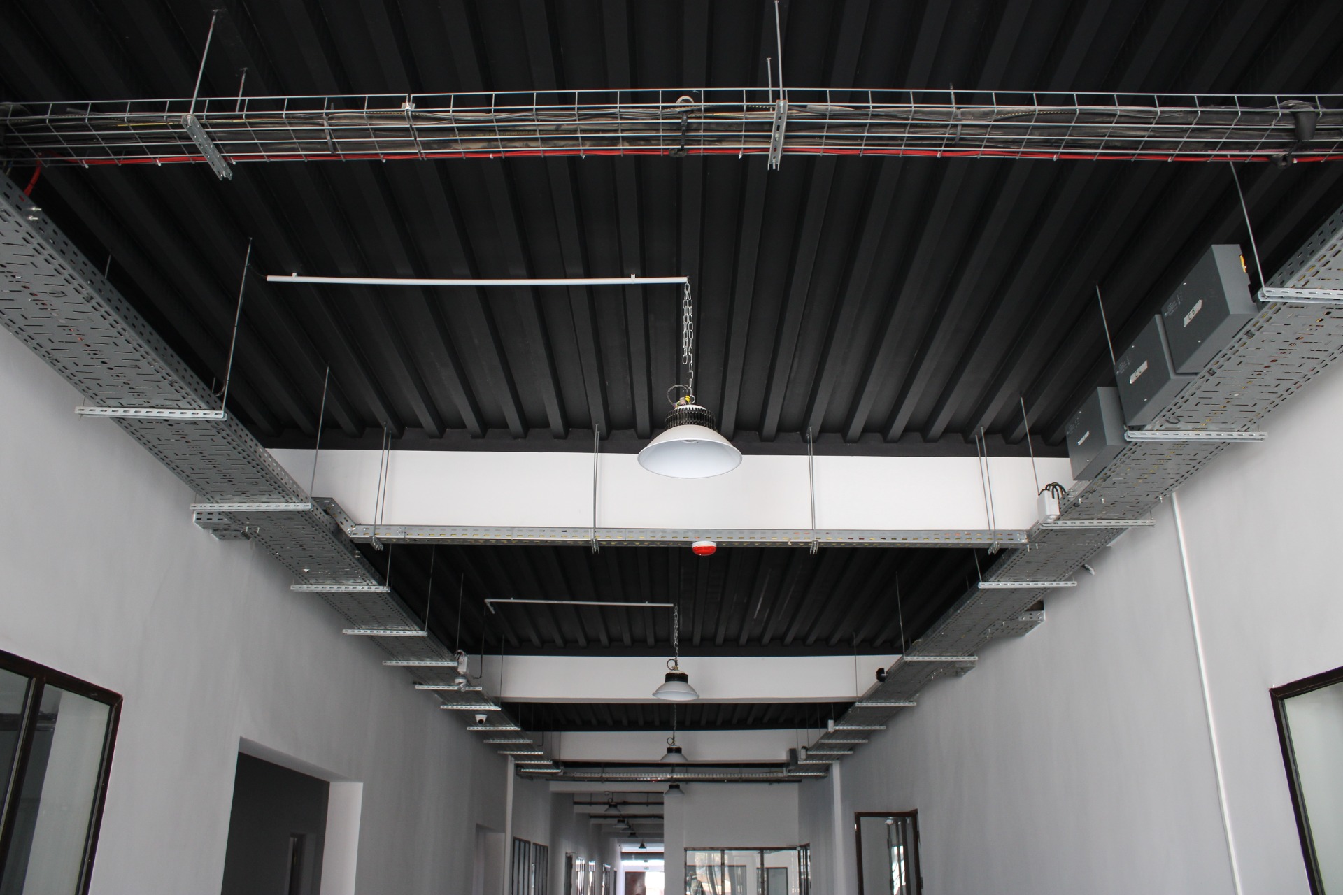 Chemins de câbles et luminaires intégrés à une installation électrique dans un bâtiment tertiaire.